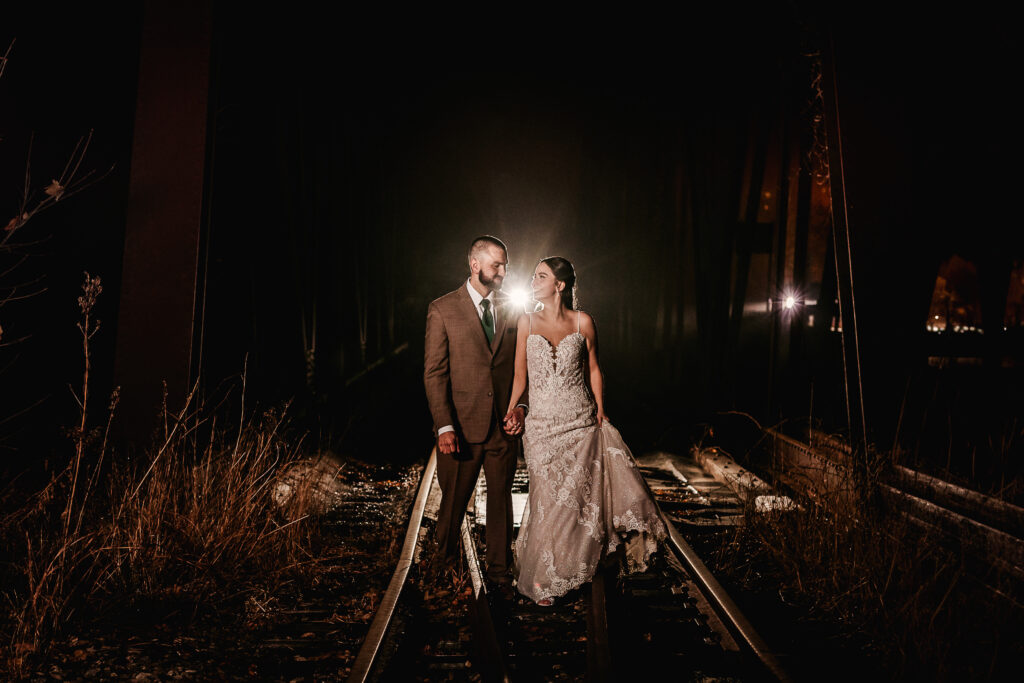 Bride and groom walking along train tracks in NH Wedding Photography creative night photography