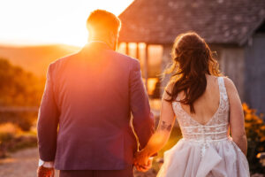 Bride and groom walking towards sunset