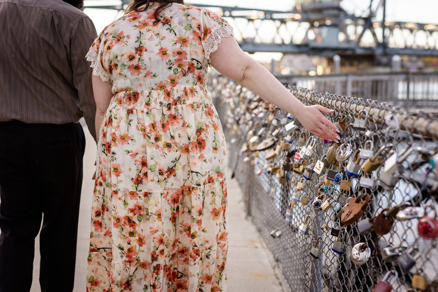 Couple walking along fence with locks also know as the love wall  in Portsmouth NH Engagement Photos by Lisa Smith Photography 