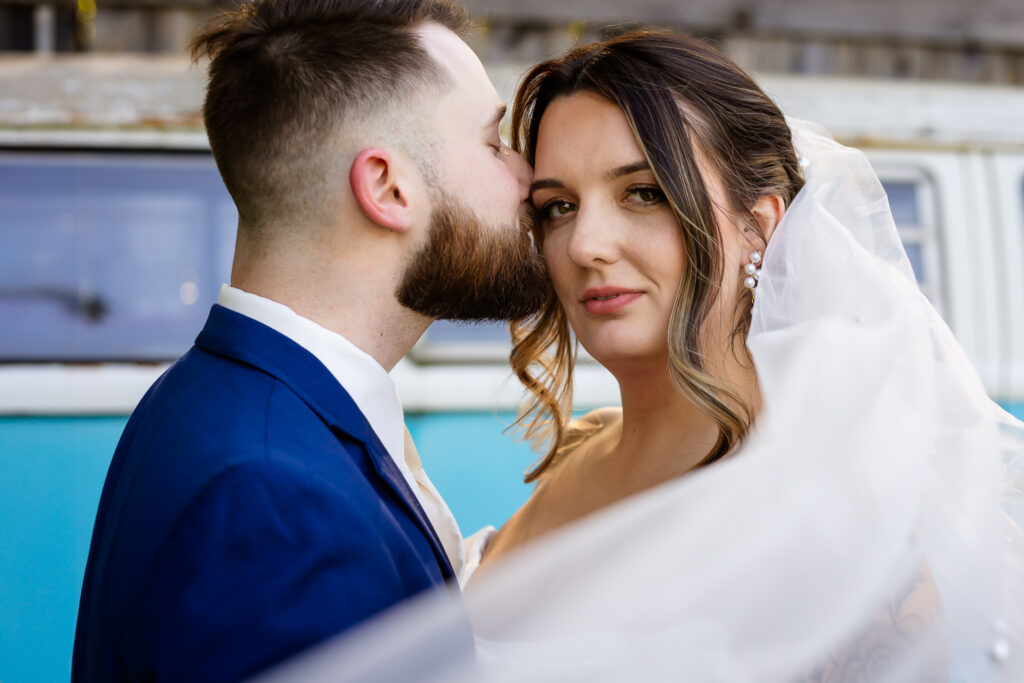 Bride looking dreamily in the camera while groom snuggles into her at Josiah's Meeting House Wedding  by Lisa Smith Photography