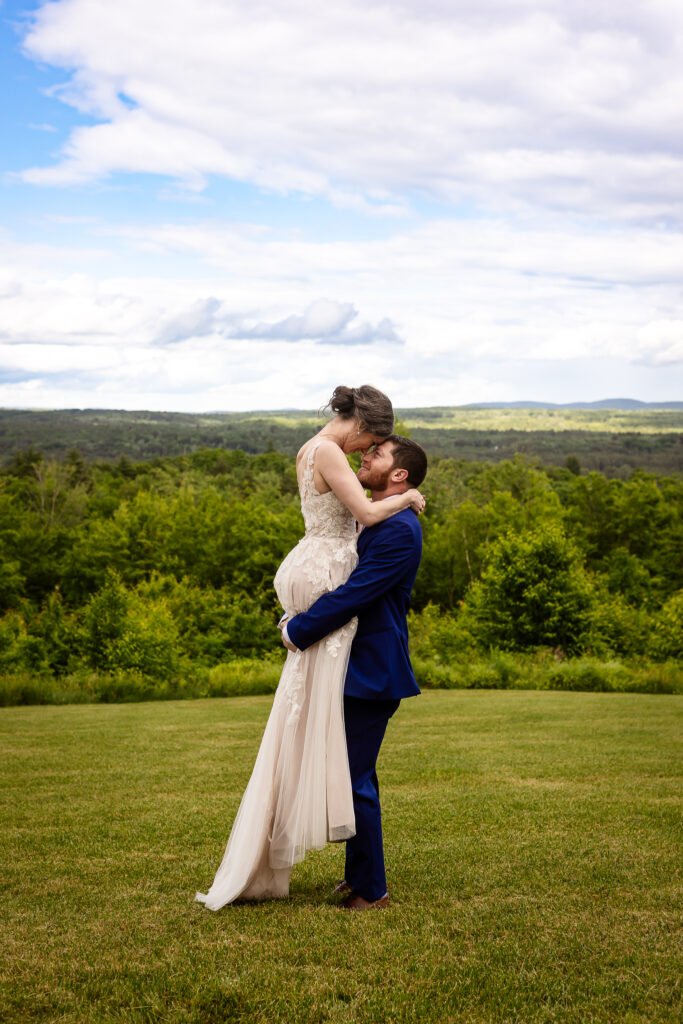 Groom lifting bride in field with stunning mountain view at ceremony site at Mountain View Stables by Lisa Smith Photography