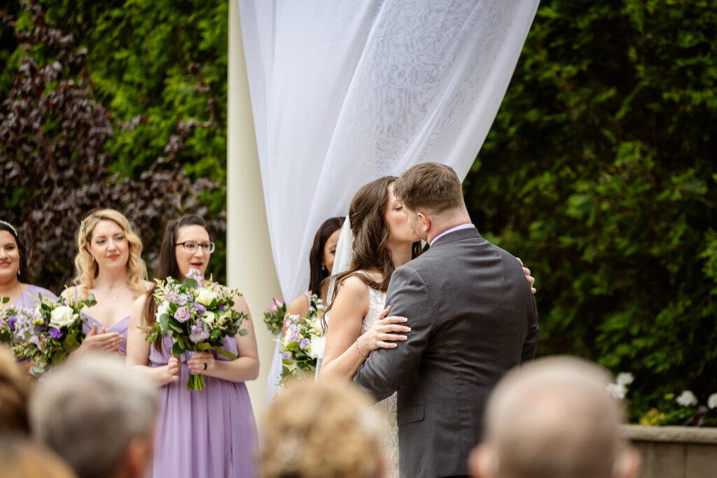 Alternative angle of bride and grooms first kiss as husband and wife during ceremony at Birchwood Vineyard in Derry NH by Lisa Smith Photography