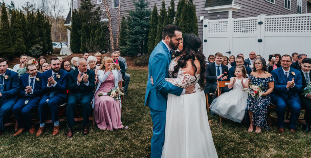 Intimate wedding ceremony with groom and brides first kiss at Bedford Village Inn with guest looking and cheering on!