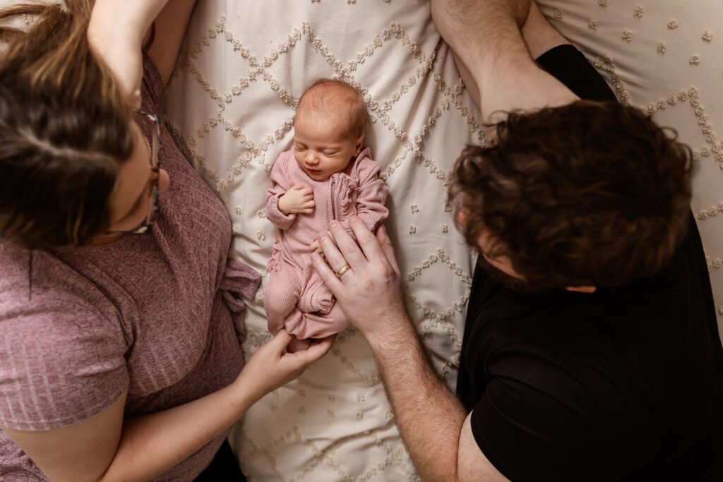 mom and dad laying on bed with newborn baby in between them by NH Newborn Photographer Lisa Smith Photography