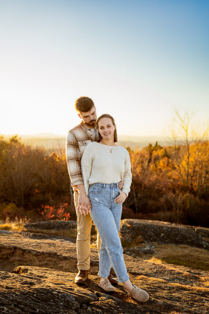 Engaged couple standing on rocks over looking the Monadnock region in southwestern NH