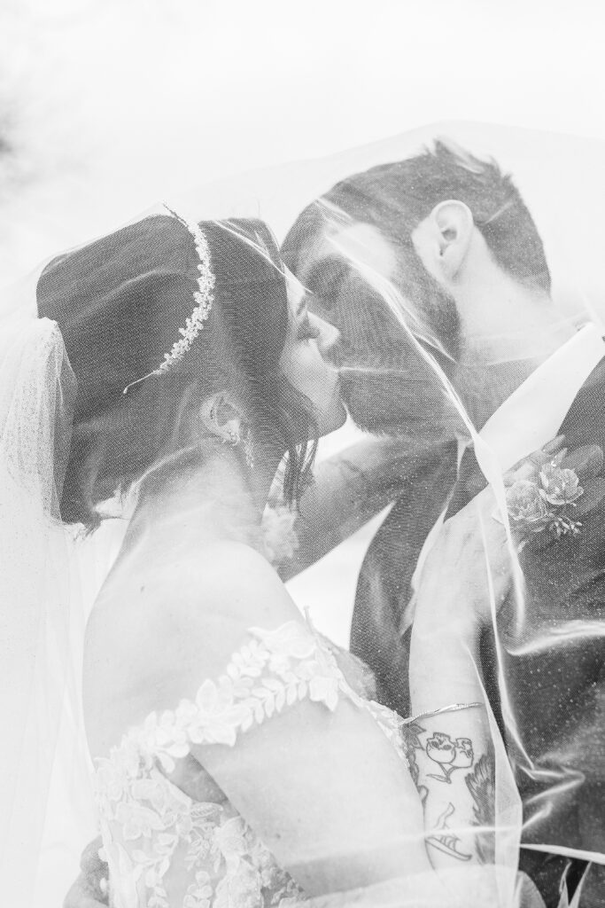 black and white image of bride and groom kissing under veil at the Inn on Main in Wolfboro NH wedding.