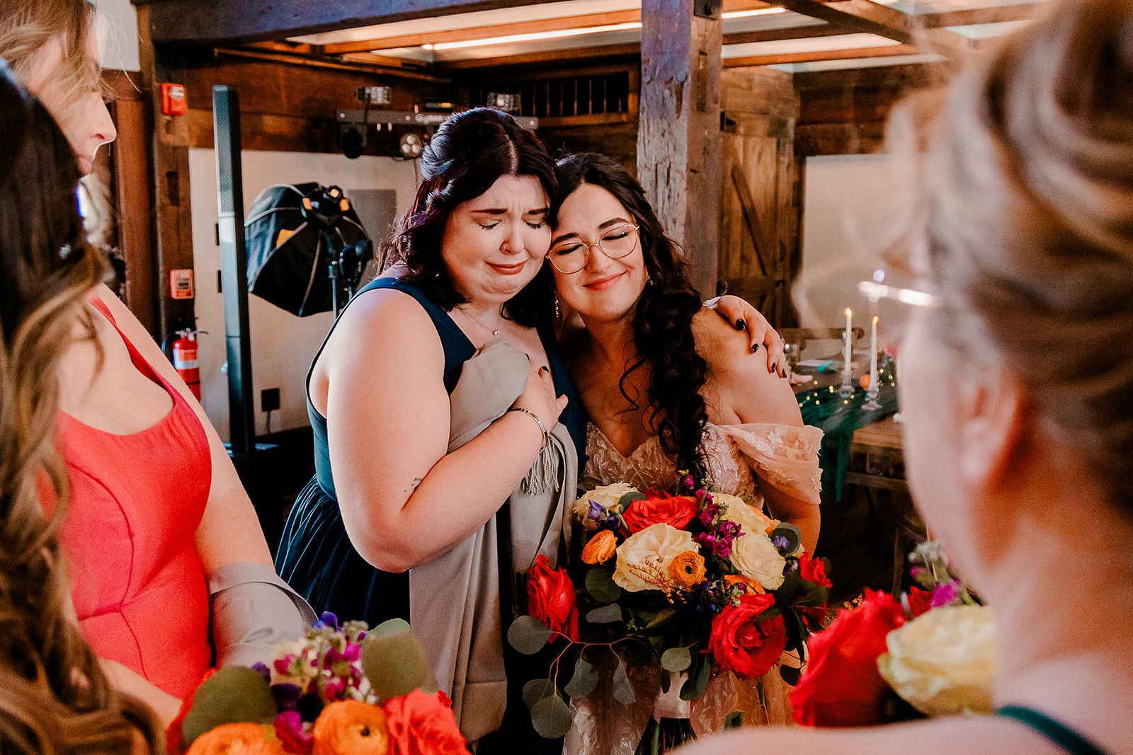 Bride and bridesmaid crying together after ceremony